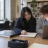 Students working through a mathematics exercise with a laptop and study notes.